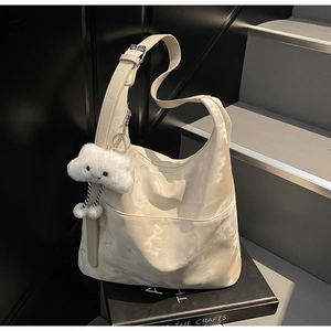 Detail of cream marble tote bag with adjustable strap and cloud plush charm decoration