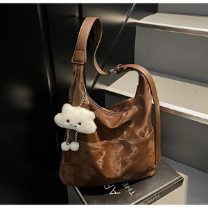 Detail of dark brown leather hobo bag with adjustable strap and plush cloud charm