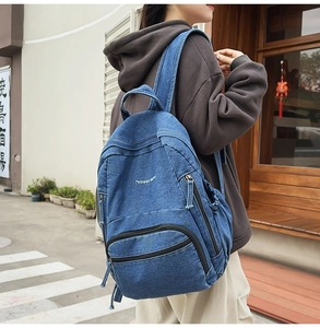 Foto exterior de una mochila de mezclilla lavada azul con logo y bolsillos laterales