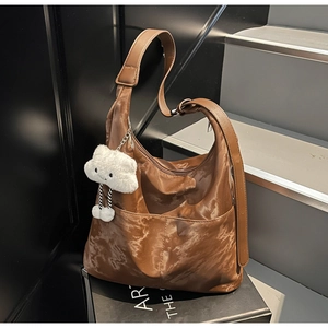 Detail of a brown marble-textured large hobo bag with front pockets and plush charm