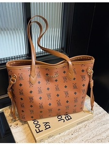 Brown tote bag with bear print and gold logo on a book background, casual fashion style