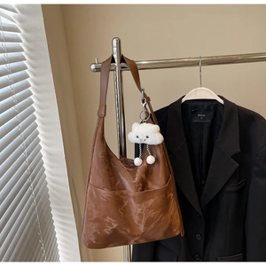 Close-up of brown faux leather hobo tote bag with front pocket and cloud plush keychain