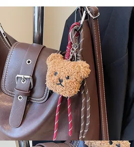 Detail eines braunen Plüschbären-Anhängers mit Kordel an einer Ledertasche