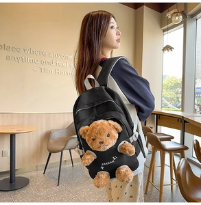 Detail of cute brown teddy bear plush ornament on black canvas backpack front pocket