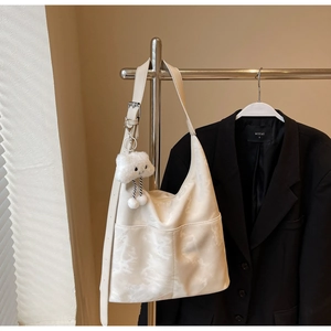 Close-up of white marble pattern tote bag with plush cloud charm on a hanger