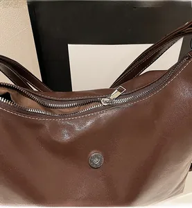 Details von Metallreißverschluss und Magnetverschluss an dunkelbrauner Ledertasche