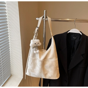 Close-up of cream tote bag with fine faux leather texture and cloud plush charm