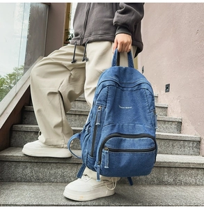 Foto exterior de una mochila de mezclilla azul con diseño multibolsillos y estilo urbano