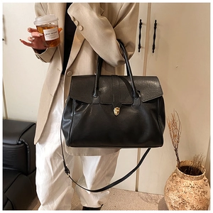 Detalle del bolso tote de cuero negro con cierre dorado y correa desmontable