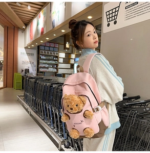 Detail of pink bear plush backpack showing side view and soft canvas texture on model
