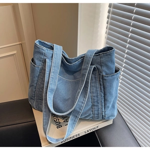 Détail d'un grand sac fourre-tout en denim bleu clair avec plusieurs poches extérieures