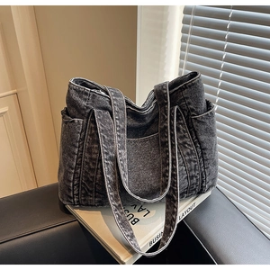 Détail du sac cabas en denim gris foncé montrant les poches latérales et le tissu délavé