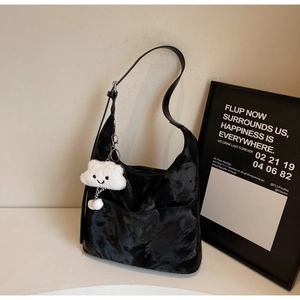 Detail of a black textured tote bag featuring a cute white cloud plush charm accessory