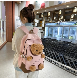 Detailed view of pink and brown backpack with a cute teddy bear in front pocket