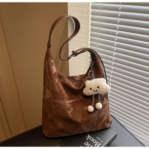 Detail of dark brown tote bag with marble texture and plush cloud charm accessory