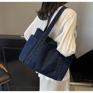 Détail du grand sac cabas en jean bleu foncé avec plusieurs poches et bandoulière