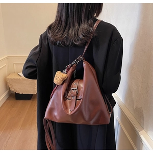 Braune Vintage-Tasche mit Metallschnalle und Plüschbär-Anhänger am Modell gezeigt