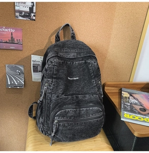 Detalle de mochila vintage en denim lavado con textura gris y un bolsillo frontal amplio