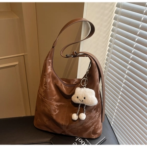 Detail of a brown marble textured tote bag with a soft white cloud plush pendant