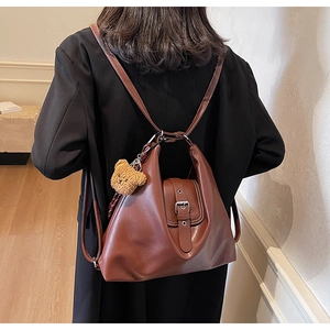Detail eines braunen Vintage-Lederrucksacks mit Silberschnalle und Plüschbär-Anhänger