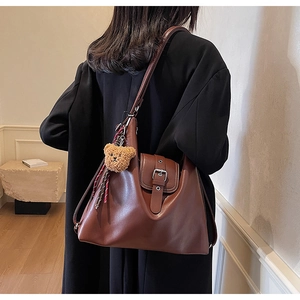 Detail der braunen Vintage-Leder-Einkaufstasche mit dekorativem Plüschbären-Anhänger