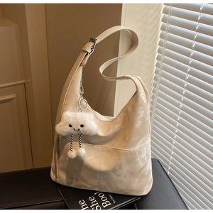 Detail of cream hobo bag featuring a cute white plush cloud charm and adjustable strap