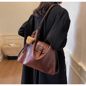 Detail der braunen Vintage-Tasche mit Plüschbärenanhänger und Retro-Schnallenverschluss