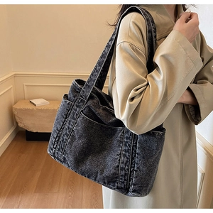 Vue latérale détaillée du grand sac cabas en denim noir délavé montrant texture et poches