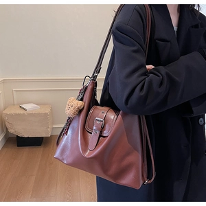 Detailansicht einer großen Vintage-Einkaufstasche aus Leder mit Schnalle und Bärenanhänger