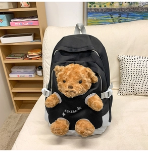 Close-up of cute brown teddy bear plush embedded in black and grey canvas school backpack