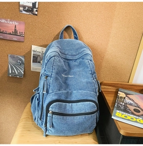Detalle de mochila de tela vaquera azul con bordado Treet Gland y varios cremalleras