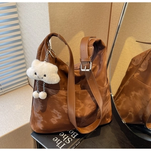 Detail view of dark brown tote bag with marble texture and plush cloud charm accessory