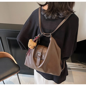 Detail eines dunkelbraunen Lederrucksacks mit Silberschnalle und Bären-Anhänger