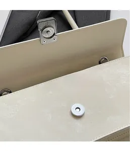 Dettaglio della chiusura magnetica e degli occhielli in argento sulla borsa beige in pelle