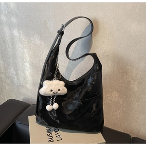 Detail of black glossy crescent tote with adjustable strap and white plush cloud charm
