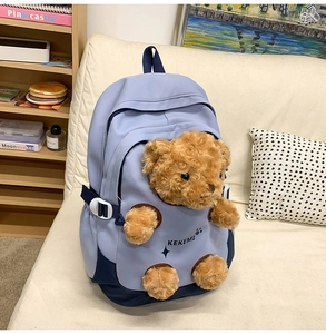 Detail of light blue school backpack with a 3D plush bear on a cozy cream sofa