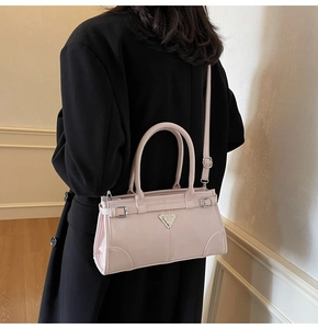 Detail view of light pink handbag with metal triangle plate on black blazer