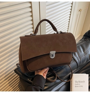 Detail of vintage brown frosted leather satchel showing silver buckle and top handle grip