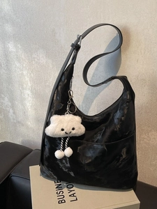 Minimalist black synthetic leather tote bag with glossy texture and plush cloud charm