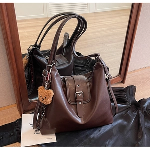 Details der braunen Vintage-Einkaufstasche mit Metallschnallen und Bärenanhänger