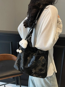 Minimalist large glossy black tote bag with white cloud plush charm worn by model
