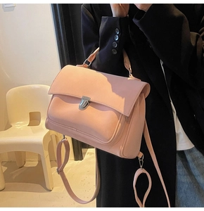 Pink matte messenger bag with silver twist lock and adjustable straps on black coat