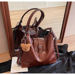 Details der braunen Vintage-Leder-Einkaufstasche mit Schnalle und Bärenanhänger