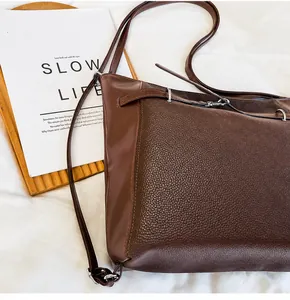 Detail view of coffee brown tote bag showing smooth leather texture and metal buckles