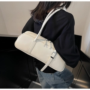 Rear view of model wearing a beige leather baguette bag with dual zippers and adjustable strap