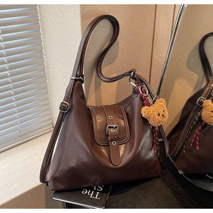 Detail der dunkelbraunen Leder-Shopper-Tasche mit süßem Teddybär-Anhänger und Bandakzent