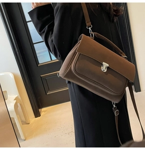 Side view of dark brown frosted leather crossbody bag with silver buckle and top handle