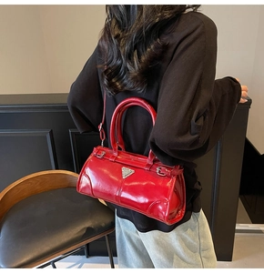 Detail of red patent leather Boston bag with silver triangle plaque and sleek handles