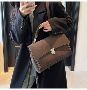 Close-up of a dark brown matte leather satchel with silver buckle and top handle detail