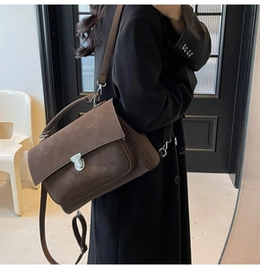 Close-up of brown matte satchel featuring a silver twist lock and adjustable shoulder strap